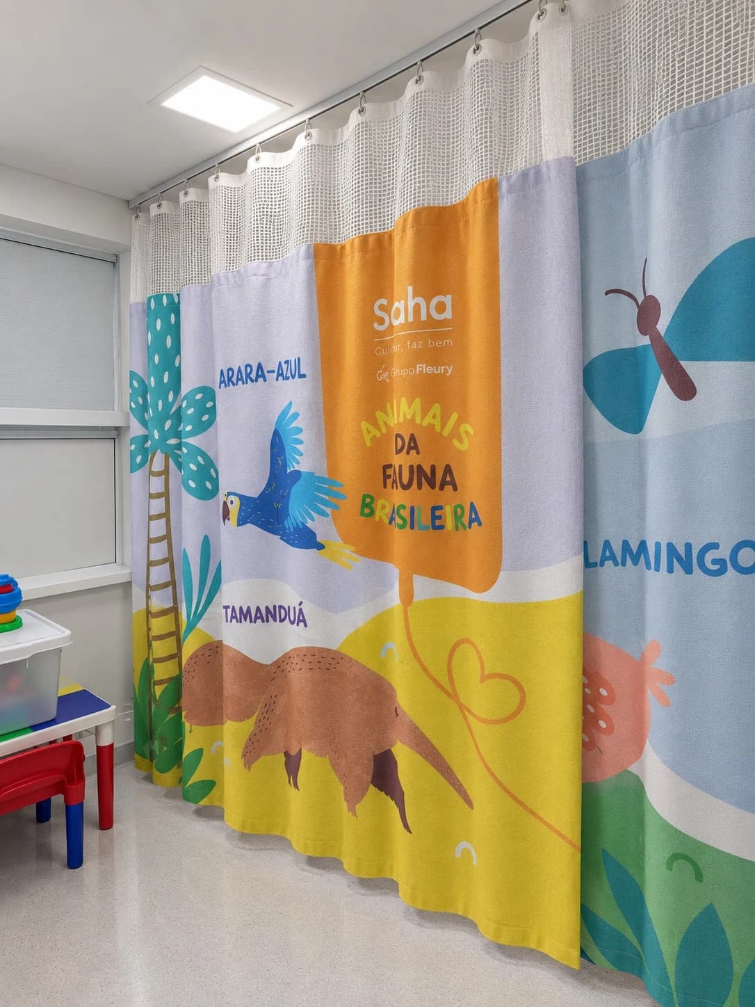 Cortina divisória hospitalar em tecido com tela superior instalada em ambiente clínico.